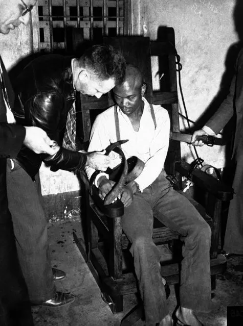 Willie Mae Bragg, first victim of the nation's only portable electric chair, looks on as he is strapped by deputies into the “Throne of death”, a few minutes before the current shot through his body at Lucedale, Mississippi on October 11, 1940. The portable electric chair was made necessary because Mississippi law calls for execution in the county where the crime, in this case wife slaying, was committed. (Photo by AP Photo)