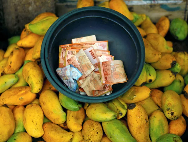 Sri Lankan currency notes are seen in a bucket at a fruits stall near a main market,in Colombo, Sri Lanka, July 29, 2016. (Photo by Dinuka Liyanawatte/Reuters)