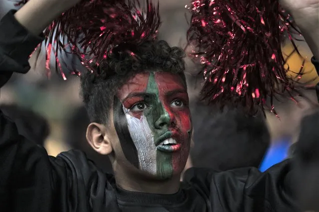 A Morocco fan with his face painted with Moroccan and Palestinian flags watches a live broadcast of the World Cup quarterfinal soccer match between Morocco and Portugal played in Qatar, in Gaza City Saturday, December 10, 2022. (Photo by Fatima Shbair/AP Photo)