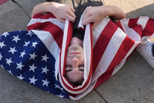 A demonstrator wraps themselves with a U.S. flag during a protest outside Dodger Stadium Saturday, June 21, 2025, in Los Angeles. (Photo by Damian Dovarganes/AP Photo)