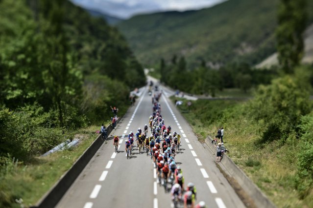 This photograph taken with a tilt-shift lens shows the pack of riders (peloton) cycling during the 18th stage of the 112th edition of the Tour de France cycling race, 171.5 km between Vif and Courchevel Col de la Loze, in the Alps, southeastern France, on July 24, 2025. (Photo by Marco Bertorello/AFP Photo)