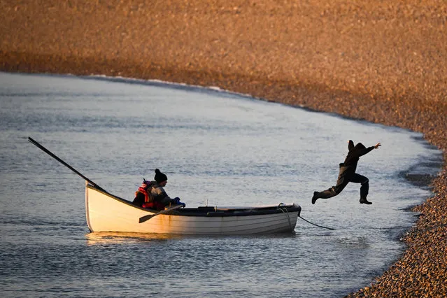A child leaps from the boat after fishermen and children return to shore upon checking their crab and lobster pots in the evening sunshine off Chesil beach, on January 27, 2023 in Portland, United Kingdom. (Photo by Finnbarr Webster/Getty Images)