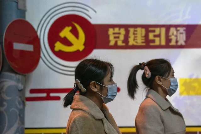 Residents wearing masks pass by the Communist party logo and the slogan “Party building leadership” in Beijing on Thursday, October 29, 2020. China will promote “technological self-reliance” under the ruling Communist Party's latest five-year plan but will open further to trade, officials said Friday. (Photo by Ng Han Guan/AP Photo)