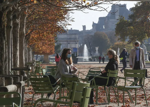 Women wearing face masks as a precaution against the coronavirus sit at the Tuileries garden in Paris, Friday, November 6, 2020. The French government is supplying quick virus tests to nursing homes around the country, amid sharply rising numbers of virus infections and deaths in care homes in recent weeks. The Louvre in the background. (Photo by Michel Euler/AP Photos)