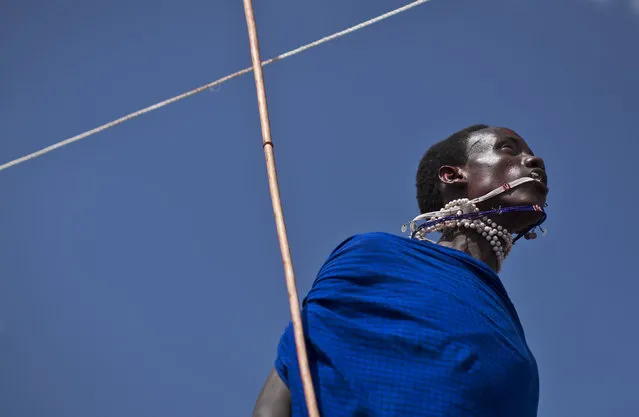 A Maasai warrior catches his swinging necklace with his mouth as he makes the high jump, in which athletes must touch a high line with the top of their heads, at the annual Maasai Olympics in the Sidai Oleng Wildlife Sanctuary near to Mt Kilimanjaro, in southern Kenya Saturday, December 13, 2014. (Photo by Ben Curtis/AP Photo)