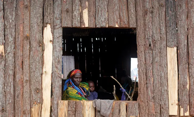 A Congolese mother, who fled from Democratic Republic of Congo by fleeing on a boat across Lake Albert, looks through a window as she carries her child at United Nations High Commission for Refugees' (UNHCR) Kyangwali refugee settlement camp, Uganda March 19, 2018. Picture taken March 19, 2018. (Photo by James Akena/Reuters)