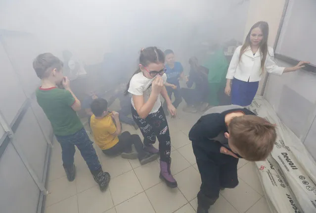 Children train how to act while haze during a free lesson on fire response held by Dmitry Kudryavtsev, a former officer of the Russian Emergency Situations Ministry, in Krasnoyarsk, Russia March 30, 2018. (Photo by Ilya Naymushin/Reuters)