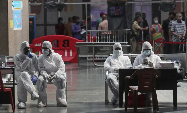 Health workers take a break from taking nasal swab samples from passengers to test for for COVID-19 at a train station in Mumbai, India, Friday, November 27, 2020. India has more than 9 million cases of coronavirus, second behind the United States. (Photo by Rafiq Maqbool/AP Photo)