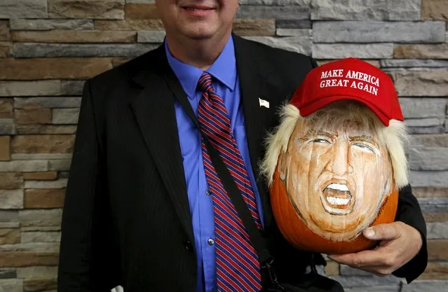 A supporter of U.S. Republican presidential candidate Donald Trump holds a pumpkin painted in the likeness of Trump as he waits to get into a campaign event in Springfield, Illinois, United States, November 9, 2015. (Photo by Jim Young/Reuters)