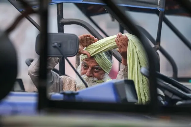 A farmer ties his turban at the site of a protest against the newly passed farm bills, at Singhu border near Delhi, India December 2, 2020. (Photo by Anushree Fadnavis/Reuters)