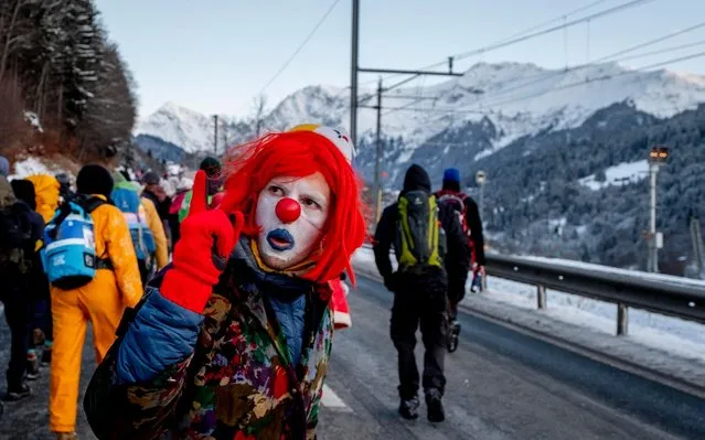 A man dressed as a clown is part of hundreds of climate protesters who are on a three-day protest march from Landquart to Davos pass the city of Klosters, Switzerland, Monday, January 20, 2020. The World Economic Forum will start on Tuesday. (Photo by Michael Probst/AP Photo)