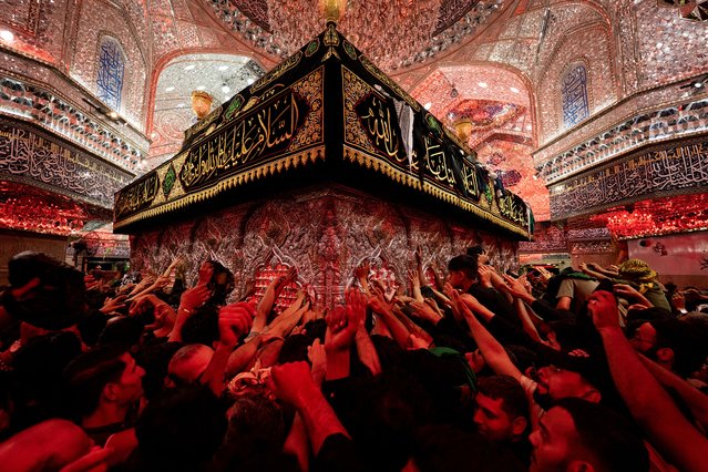 Shiite Muslim devotees reach to receive a blessing from the tomb of Imam Hussein, the Prophet Mohammed's grandson, at the Imam's shrine in Iraq's central holy city of Karbala on August 14, 2025, on the even of the Arbaeen religious festival commemorating his seventh century killing. (Photo by Hussein Faleh/AFP Photo)