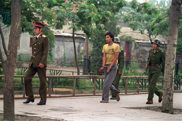 A handcuffed man is led by Chinese soldiers on a street in Beijing, in June of 1989, as police and soldiers searched for people involved in the April-June pro-democracy protests. (Photo by Manuel Ceneta/AFP Photo)