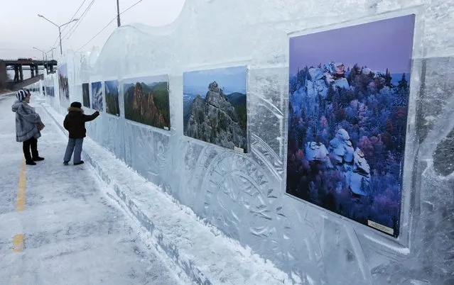 A woman and a boy look at photographs from Siberian photographers on a wall of ice, during an exhibition that is part of the “Magic Ice of Siberia” International Competition of Snow Sculpture along the banks of the Yenisei River in Krasnoyarsk January 13, 2015. (Photo by Ilya Naymushin/Reuters)