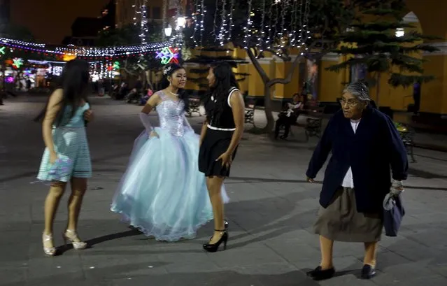 A woman (R) walks past girls dressed for a party in downtown Lima, December 7, 2015. (Photo by Mariana Bazo/Reuters)