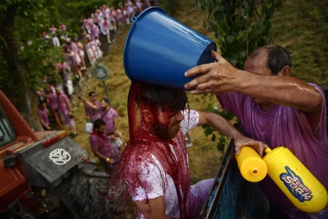 A man has red wine thrown on him as he takes part in a wine battle, in the small village of Haro, northern Spain, Friday, June 29, 2018. (Photo by Alvaro Barrientos/AP Photo)