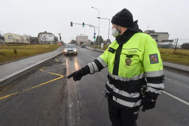 A police officer stops a car on a road between the towns, Ostrava and Opava, near Dehylov, Czech Republic Monday, March 1, 2021. Limits for free movement of people are set in the Czech Republic. Travelling to other counties unless the go to work or have to take care about relatives is prohibited. (Photo by Jaroslav Ozana/CTK via AP Photo)