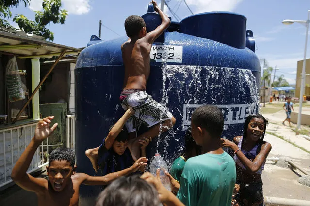 Children play under the water that they manage to spill over from a water tank, to cool off from the summer heat, at the Alemao Complex slum in Rio de Janeiro, Brazil, Thursday, January 29, 2015. State Environment Secretary Andre Correa acknowledged the region is “experiencing the worst water crisis in its history”, but said water provisioning would continue as normal through July. (Photo by Leo Correa/AP Photo)