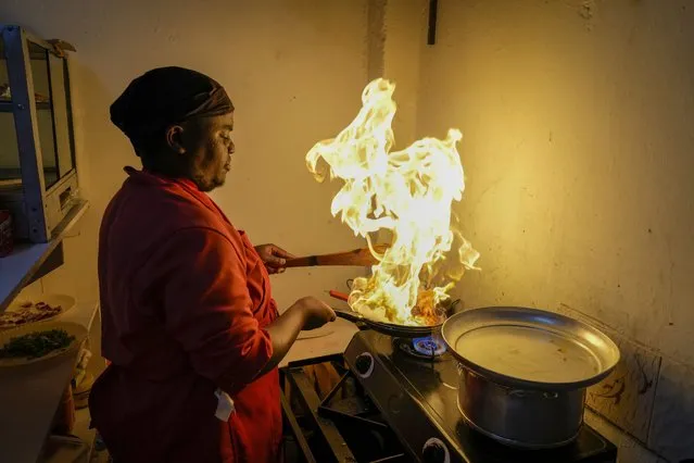 Chef and owner Mark Kioko works in the kitchen of his restaurant in Kitengela, on the outskirts of the capital Nairobi, Kenya, Monday, April 17, 2023. Kioko says he has had to increase prices, and in some cases decrease portion size of items like chapatis, due to persistently high prices of food and cooking oil. (Photo by Khalil Senosi/AP Photo)