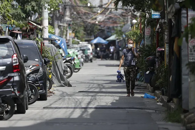 A man walks along an empty street at a village that was placed under lockdown due to the number of COVID-19 cases among residents in Manila, Philippines on Thursday, March 11, 2021. The Philippine capital placed two villages and two hotels on lockdown Thursday and police have renewed warnings against kissing and other “public display of affection” after a new surge in coronavirus infections. (Photo by Aaron Favila/AP Photo)