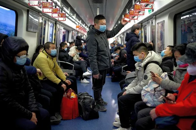 Passengers wearing face masks ride the subway in Beijing on March 3, 2021. (Photo by Noel Celis/AFP Photo)