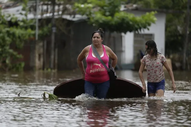 Maria Cristina Olivera, left, and her daughter Catherin carry a table on a flooded street as they leave thier home in San Miguel neighborhood in Asuncion, Paraguay, Sunday, December 27, 2015. Widespread floods have forced nearly 140,000 people from their homes in Paraguay, Argentina, Uruguay and Brazil following days of torrential rains that drenched a region where the countries border each other. (Photo by Jorge Saenz/AP Photo)