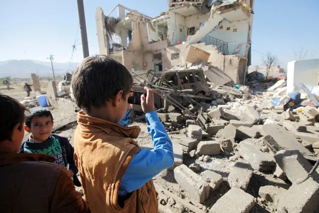 A boy uses a cell phone to take photos of the wreckage of a house destroyed by a Saudi-led air strike on the outskirts of Sanaa, Yemen, November 13, 2016. (Photo by Mohamed al-Sayaghi/Reuters)