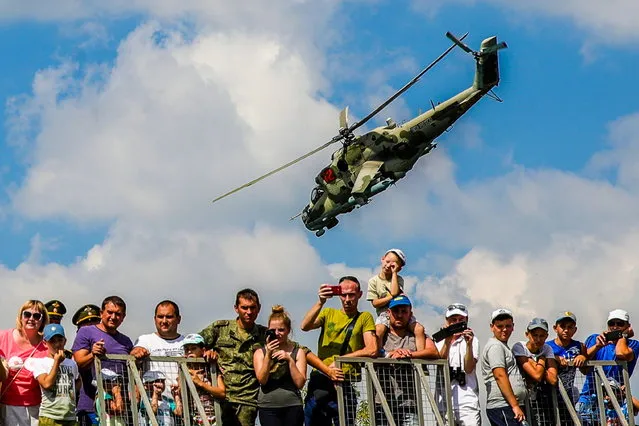 A helicopter over visitors during the Open Water contest between pontoon bridge units at the 2018 International Army Games on the Oka River, Vladimir Region, Russia, August 3, 2018. (Photo by Sergei Bobylev/TASS via Getty Images)