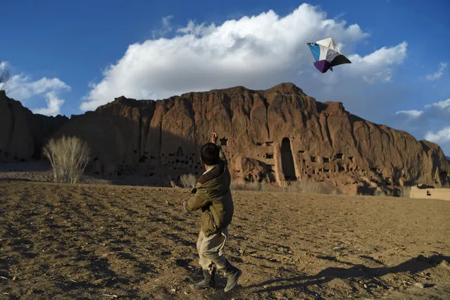 A Hazara boy flies a kite near the site of the giant Buddha statues, which were destroyed by the Taliban in 2001, in Bamiyan province on March 3, 2021. (Photo by Wakil Kohsar/AFP Photo)