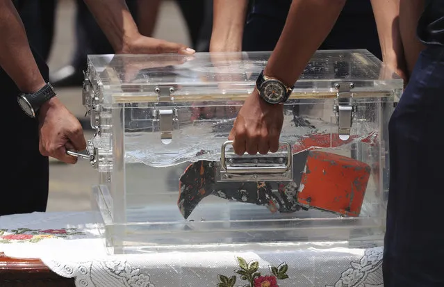 National Transportation Safety Committee investigators carry a box containing the cockpit voice recorder of Sriwijaya Air flight SJ-182 retrieved from the waters off Java Island where the passenger jet crashed in January, during a press conference at Tanjung Priok Port in Jakarta, Indonesia, Wednesday, March 31, 2021. (Photo by Tatan Syuflana/AP Photo)