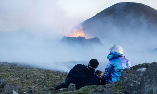 This picture taken on July 12, 2023 shows people watch smoke billow from lava during an volcanic eruption at Litli Hrutur, south-west of Reykjavik in Iceland. A volcano erupted near Iceland's capital on July 10, 2023, the country's meteorological office said, marking the third time in two years that lava has gushed out in the area. Local media footage shows a massive cloud of smoke rising from the ground as well as a substantial flow of lava at the site around 30 kilometres (19 miles) from Reykjavik. (Photo by Jeremie Richard/AFP Photo)