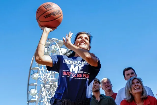 Nikki Haley shoots a basketball during a carnival game as she tours Thrillville at the Iowa State Fair with Senator (R-IA) Joni Ernst and her son Nalin in Des Moines on August 12, 2023. (Photo by Evelyn Hockstein/Reuters)