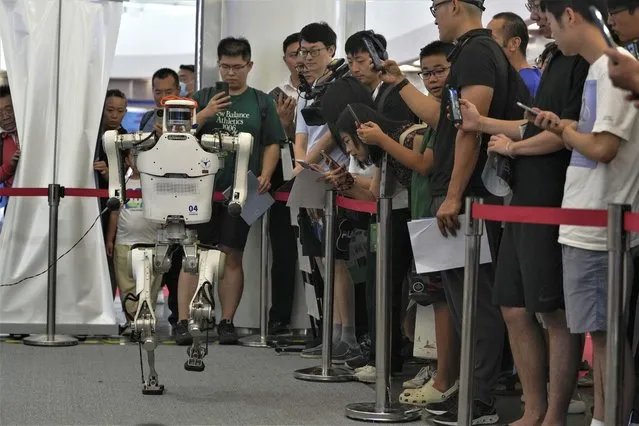 Visitors look at a remote control robot perform a walk during the annual World Robot Conference at the Etrong International Exhibition and Convention Center on the outskirts of Beijing, Thursday, August 17, 2023. (Photo by Andy Wong/AP Photo)