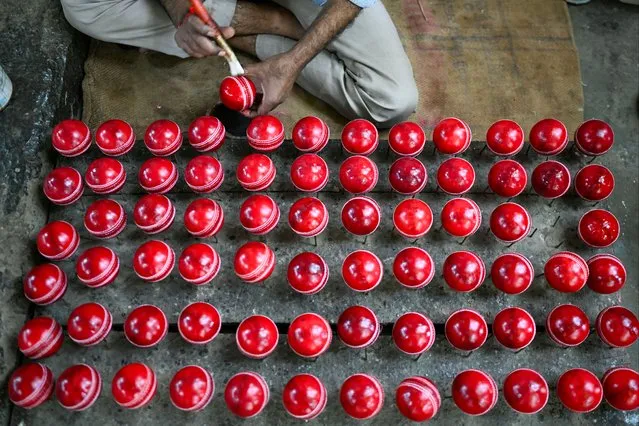 In this photograph taken on September 14, 2023, a worker polishes cricket balls at a workshop in Meerut in India's northern state of Uttar Pradesh. In a Hindu-majority nation where many view cows as sacred, those on the lower rungs of India's traditional caste hierarchy have taken on the important trade of making cricket balls. (Photo by Money Sharma/AFP Photo)