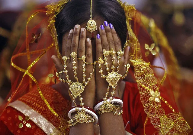 A bride covers her face as she waits to take her wedding vow at a mass marriage ceremony at Bahirkhand village, Kolkata February 8, 2015. (Photo by Rupak De Chowdhuri/Reuters)