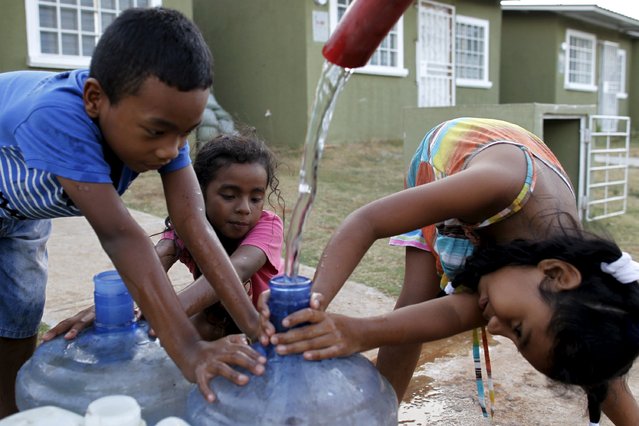 Children hold a container as water is distributed in the neighborhood of Residencial los Jardines in Panama City March 20, 2015. Residents say that there has been no running water to their homes since January 2015 and that they have relied on water tank trucks that distribute water to their neighbourhood. (Photo by Carlos Jasso/Reuters)