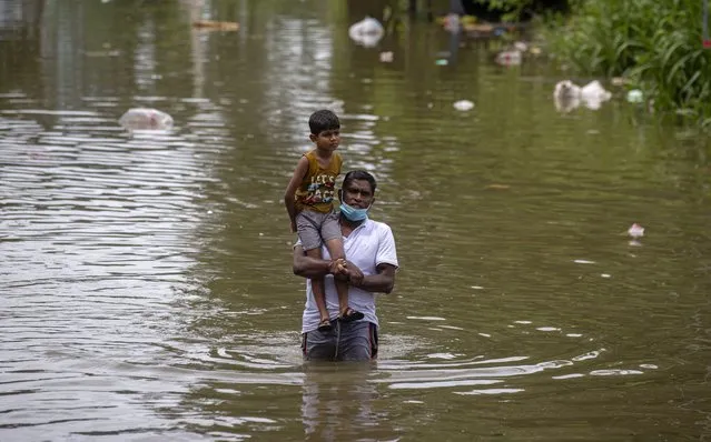A Sri Lankan man wades through in an inundated street carrying a child following heavy rainfall at Malwana, on the outskirts of Colombo, Sri Lanka, Saturday, June 5, 2021. Flash floods and mudslides triggered by heavy rains in Sri Lanka have killed at least four people and left seven missing, while more than 5,000 are displaced, officials said Saturday. Rains have been pounding six districts of the Indian Ocean island nation since Thursday night, and many houses, paddy fields and roads have been inundated, blocking traffic. (Photo by Eranga Jayawardena/AP Photo)