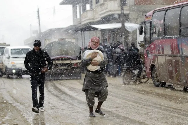 A man carries a bag of bread during a snow storm  in Kafranbel town in the Idlib governorate January 15, 2015. (Photo by Khalil Ashawi/Reuters)