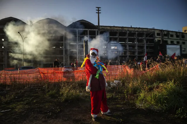 An African migrant dressed as Santa Claus stays out the abandoned penicillin factory during the evacuation on December 10, 2018 in Rome, Italy. Municipal police, Italian Police, Carabinieri, and firefighters took part in the eviction from the abandoned penicillin factory where until a few days ago about 500 people including African migrants, Italians and Roma families lived in poor hygienic conditions. (Photo by Antonio Masiello/Getty Images)