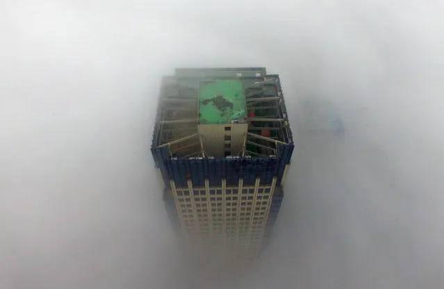 A building appears through a thick layer of fog in Yangzhou, in China's eastern Jiangsu province on January 2, 2017.  Thick fog reduced visibility in the city, sometimes down to 50 meters. (Photo by AFP Photo/Stringer)