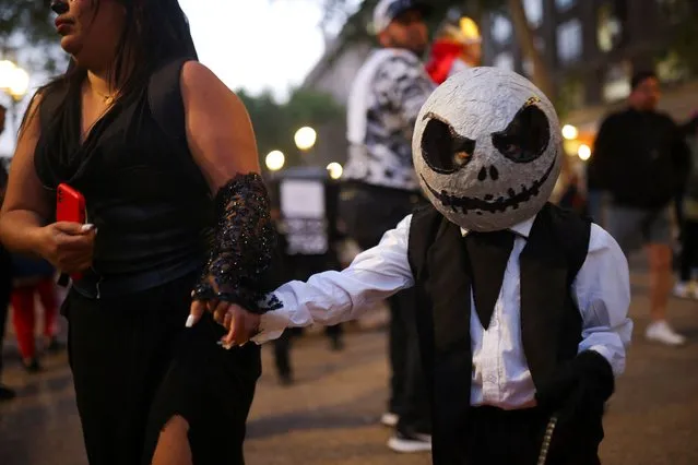 A child in a Halloween costume goes trick or treating in the streets of Santiago, Chile on October 31, 2023. (Photo by Pablo Sanhueza/Reuters)