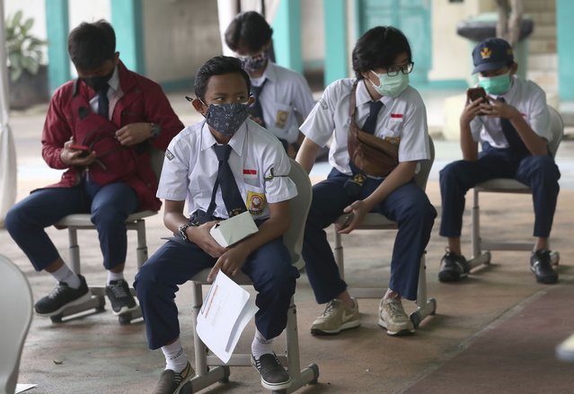 Students wearing masks to help curb the spread of coronavirus wait for their turn to receive a shot of the Sinovac COVID-19 vaccine during a vaccination campaign for children between 12-17 years of age at a school in Tangerang, Indonesia, Wednesday, July 14, 2021. The world's fourth most populous county is struggling to acquire enough vaccines to reach its target of inoculating more than 181 million of its 270 million people by March 2022. (Photo by Tatan Syuflana/AP Photo)