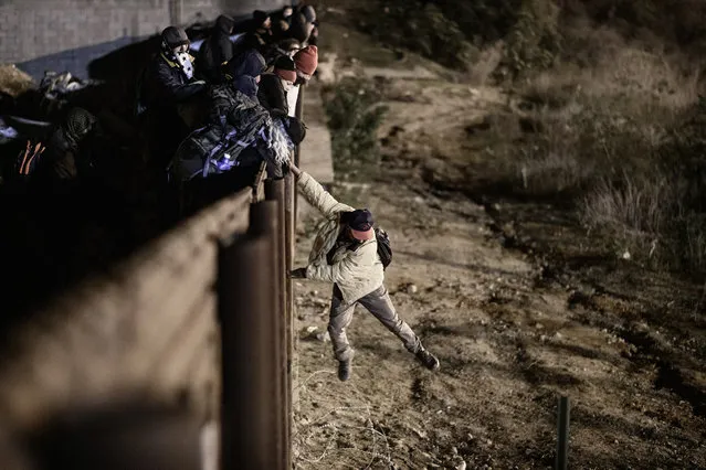 A migrant jumps the border fence to get into the U.S. side to San Diego, Calif., from Tijuana, Mexico, Tuesday, January 1, 2019. Discouraged by the long wait to apply for asylum through official ports of entry, many migrants from recent caravans are choosing to cross the U.S. border wall and hand themselves in to border patrol agents. (Photo by Daniel Ochoa de Olza/AP Photo)
