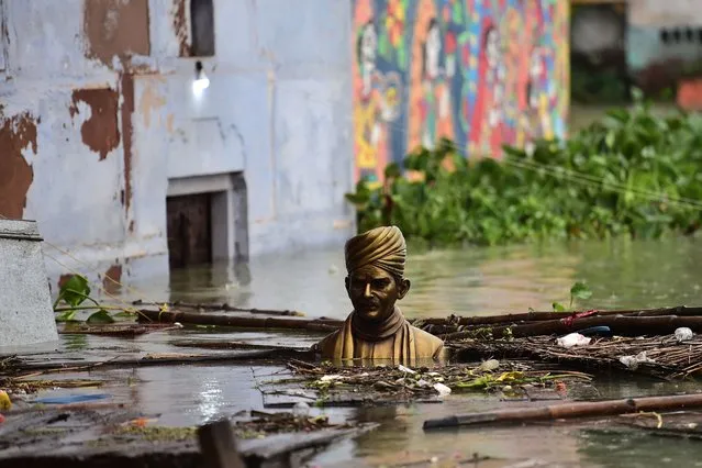 A statue of Indian scholar, educational reformer and politician Pandit Madan Mohan Malaviya is seen submerged in flood waters on the banks of the Ganges River as the water level of the Ganges and Yamuna rivers has risen, in Allahabad on August 11, 2021. (Photo by Sanjay Kanojia/AFP Photo)
