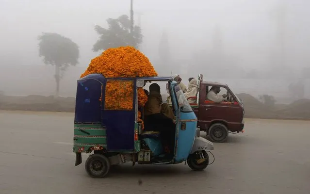 A Pakistani man drives an auto rickshaw carrying flowers, in Peshawar, Pakistan, Thursday, December 19, 2013. The dense fog disrupted flights, train schedules, and forced authorities to close several highway sections in Pakistan. (Photo by Mohammad Sajjad/AP Photo)