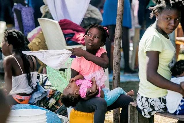 A girl holds another child at an encampment set up on a soccer field after Saturday's 7.2 magnitude quake, in Les Cayes, Haiti on August 16, 2021. (Photo by Ralph Tedy Erol/AP Photo)