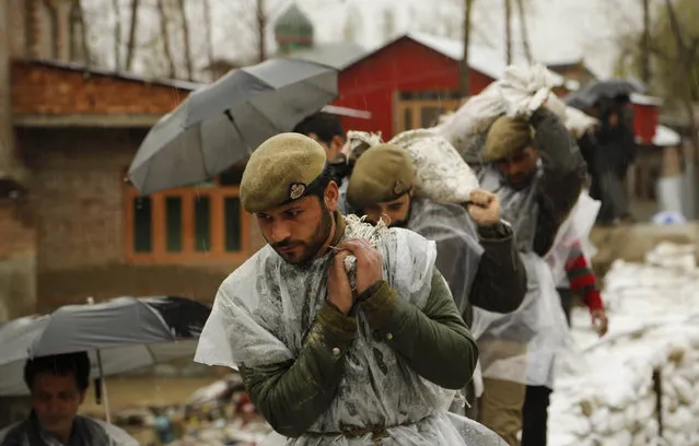 Jammu and Kashmir policemen carry sand bags to repair a breach in an embankment in a flooded area of Srinagar, Indian-controlled Kashmir, Wednesday, April 1, 2015. Although flood waters were receding, residents in the main city of Srinagar were bracing for more trouble as the meteorological office has predicted more rain over the next few days. (Photo by Mukhtar Khan/AP Photo)