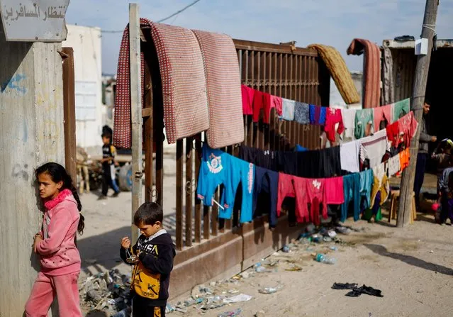 Children stand next to clothes hanging on lines as displaced Palestinians who fled their homes due to Israeli strikes shelter at Rafah crossing on the border with Egypt, amid the ongoing conflict between Israel and the Palestinian Islamist group Hamas, in Rafah in the southern Gaza Strip on December 8, 2023. (Photo by Mohammed Salem/Reuters)