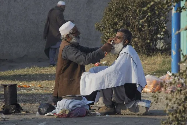 A Pakistani roadside barber attends to a customer in Peshawar, Pakistan, Wednesday, February 3, 2016. (Photo by Mohammad Sajjad/AP Photo)