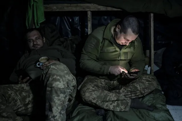 Ukrainian service members rest inside a dugout at a position near the frontline town of Bakhmut in Donetsk region, Ukraine on December 21, 2023. (Photo by Viacheslav Ratynskyi/Reuters)